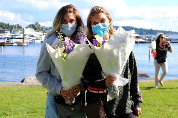 Two young ladies wearing facemasks holding flowers at Marina Park