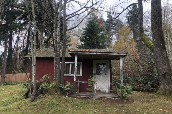 Small red cottage with lots of plant growth